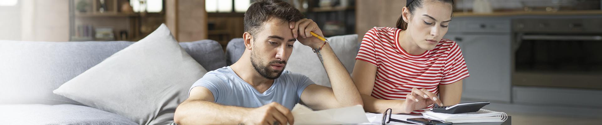 Man and woman in lounge looking concerned at papers
