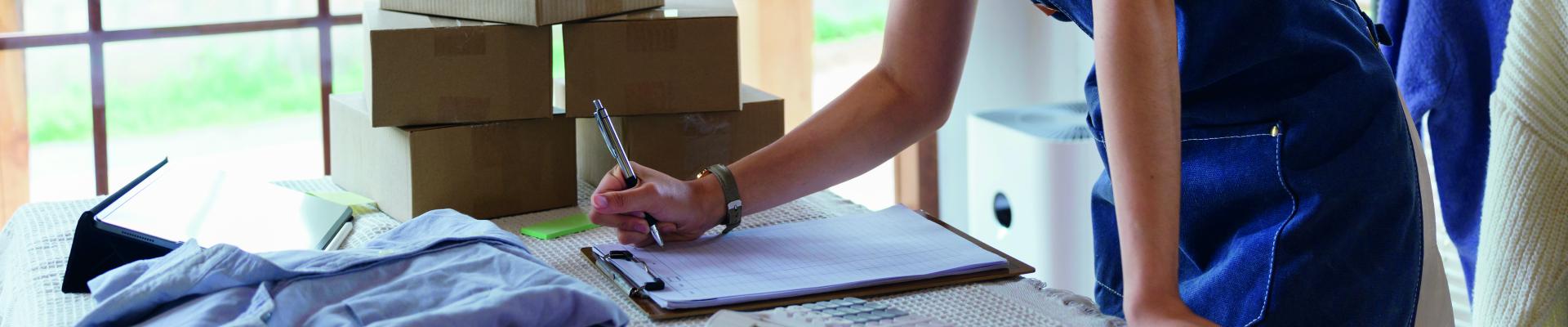 Woman holding a pen and writing on a pad